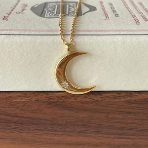 Elegant gold crescent moon necklace with star pendant and white zircon on wooden surface