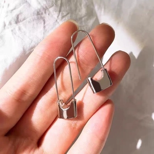 Detailed view of silver paperclip earrings held by hand to show product size and polished finish