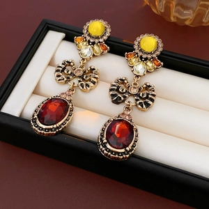 Detailed close-up of vintage gold earrings with red oval stones and yellow bow accents