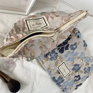 Détail de grandes trousses de maquillage en jacquard floral avec fermeture éclair en métal