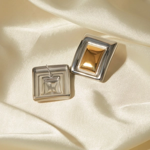 Minimalist rectangular earrings in gold and silver finish on elegant silk background