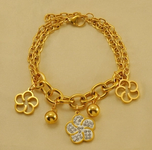 Détail d'un bracelet double chaîne plaqué or 18k avec fleur en cristal et breloques