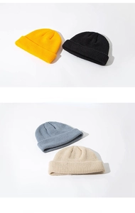 Pile of knitted docker hats in yellow, black, navy blue and beige colors for winter