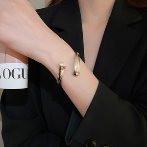 Close-up of a silver water drop leaf open bangle on a model wearing a black suit