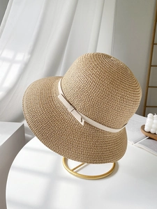 Detailed close-up of straw sun hat weaving with elegant bow and cream ribbon detail