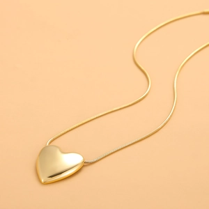 Detailed close-up of gold heart pendant necklace featuring a polished snake chain