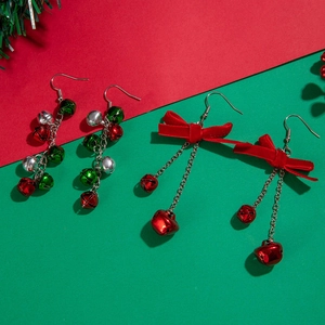 Detailed view of Christmas earrings with red and green bells and festive bows