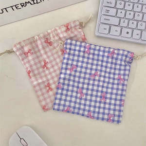 Detail of gingham drawstring storage bags with bow patterns on a clean desktop