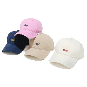 Detail of four colorful baseball caps with OKEY embroidery and distressed brim finish