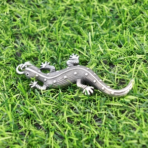 Gros plan détaillé d'un pendentif gecko 3D vintage avec textures à pois sur herbe verte