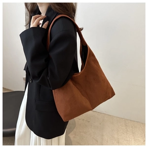 Brown suede tote bag on model's shoulder showing large capacity and premium texture