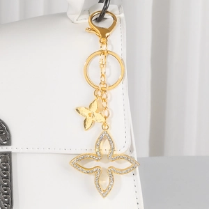Close-up of golden four-leaf clover keychain with rhinestones on a white leather bag