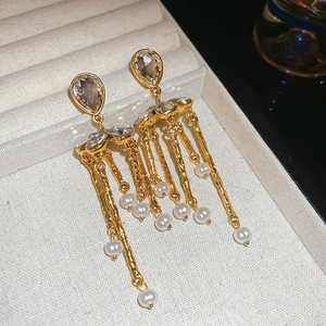 Élégantes boucles d'oreilles dorées à pompons avec cristal goutte et perles sur plateau