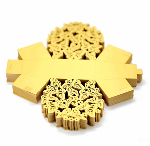 Detailed macro view of laser-cut butterfly patterns on gold wedding favor boxes