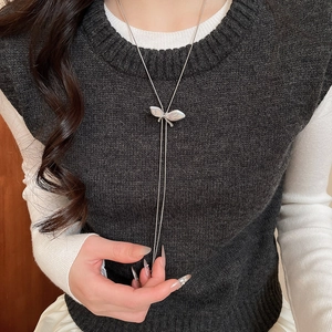 Detailed close-up of a silver butterfly pearl pendant long necklace on a model clothing