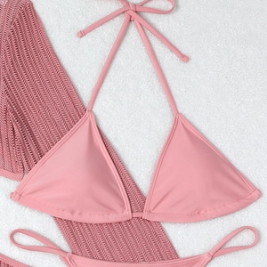 Flat lay of pink three-piece bikini set with hollow out drawstring knit cover-up