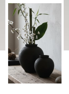 Gros plan de vases en céramique noir mat style wabi-sabi sur surface en bois
