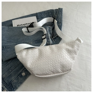 Detail of white woven texture crossbody bag on blue denim jacket in a casual setting
