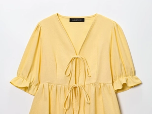 Detail of French style puff sleeves and V-neck with lace-up bow on yellow shirt