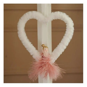 Detail of plush heart ornament with a pink feather ballerina hanging on a white pillar