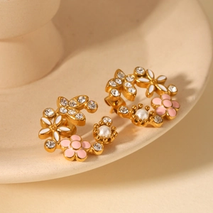 Détail macro de boucles d'oreilles fleur 18K avec émail rose, zircons et perles