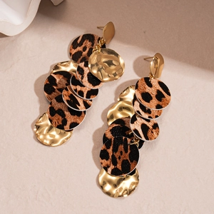 Detail of bohemian gold earrings with layered leopard print discs and metallic texture