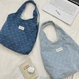 Detailansicht der Denim-Taschen mit Schleifenmuster und Lifestyle-Accessoires auf weißem Stoff