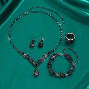 Detailed macro view of black rhinestone jewelry set with water drop pendants on green silk