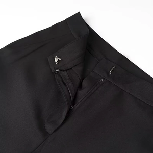 Detail of the waist closure featuring metal hook and zipper on black trousers