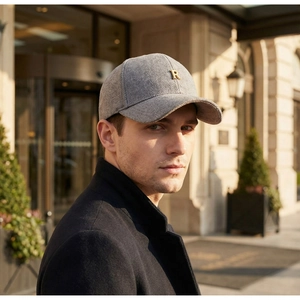 Close-up of grey herringbone baseball cap with gold metal R logo and wool texture