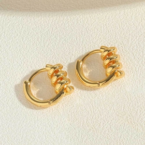 Macro view of gold hoop earrings featuring elegant spiral twisted texture and high polish
