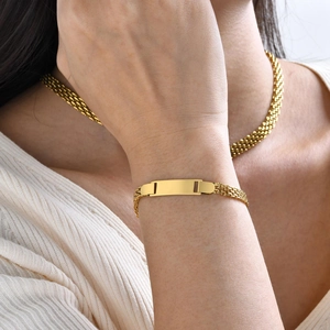 Close-up of golden mesh bracelet and necklace set with rectangle ID plates on model
