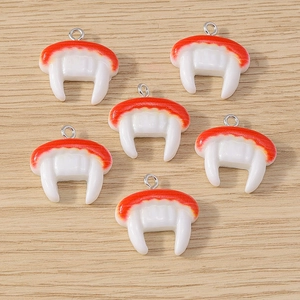 Detailed view of red and white vampire fang charms for Halloween DIY jewelry making