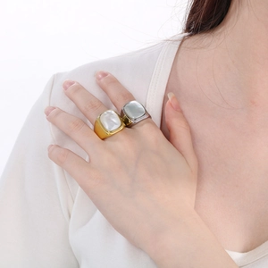 Detail of square white shell inlay on gold and silver stainless steel rings worn by model