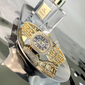Detailed close-up of a gold oval quartz watch featuring sparkling rhinestones on the band