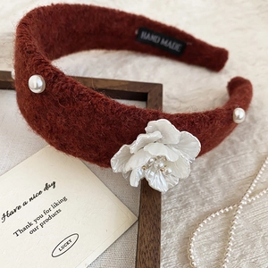 Detail of red plush headband with delicate white floral accents and elegant pearls