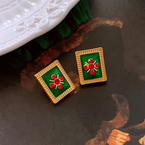 Macro shot of vintage style earrings with green enamel and red crystal cross pattern