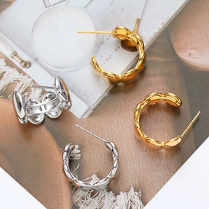Polished wave-shaped C-loop earrings in gold and silver finish on a stylish background
