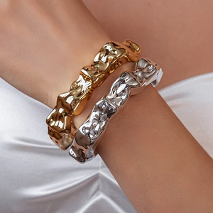 Detailed close-up of gold and silver irregular wave bracelets on a model wrist