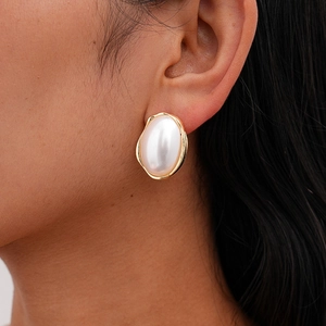 Gros plan d'une boucle d'oreille en perle baroque avec cadre doré irrégulier et style rétro
