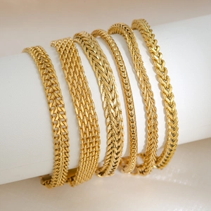 Gold-plated stainless steel Cuban and mesh link bracelets on a display stand