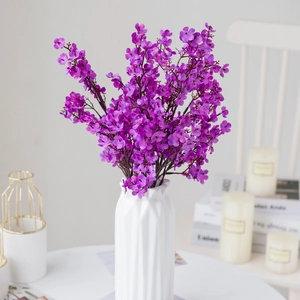 Close-up of purple artificial baby's breath flowers in a white textured vase decor