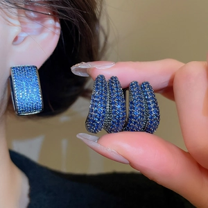 Close-up of Klein Blue zircon U-shaped double hoop earrings on model ear with sparkling details