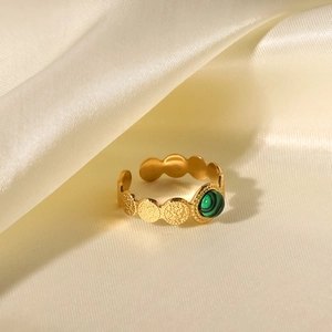 Close-up of 18K gold-plated ring with round green malachite stone on silk fabric