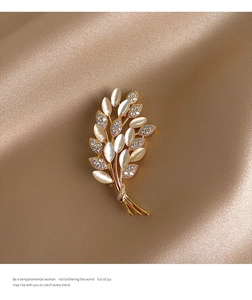 Macro shot of gold wheat brooch with cat eye stone and rhinestones on silk