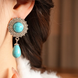 Close-up of vintage double-layer turquoise drop earrings with crystals on a female model