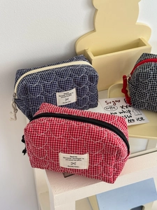 Gros plan sur la broderie cœur matelassée des trousses de maquillage à carreaux multicolores