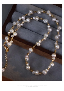 Detail of woven double-layer pearl necklace with golden metal beads and extension chain