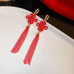 Detail of red Chinese knot earrings with golden tassels and zircon-encrusted hoops