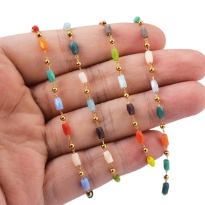 Detail of colorful long stone beads and golden spacers on stainless steel chain link